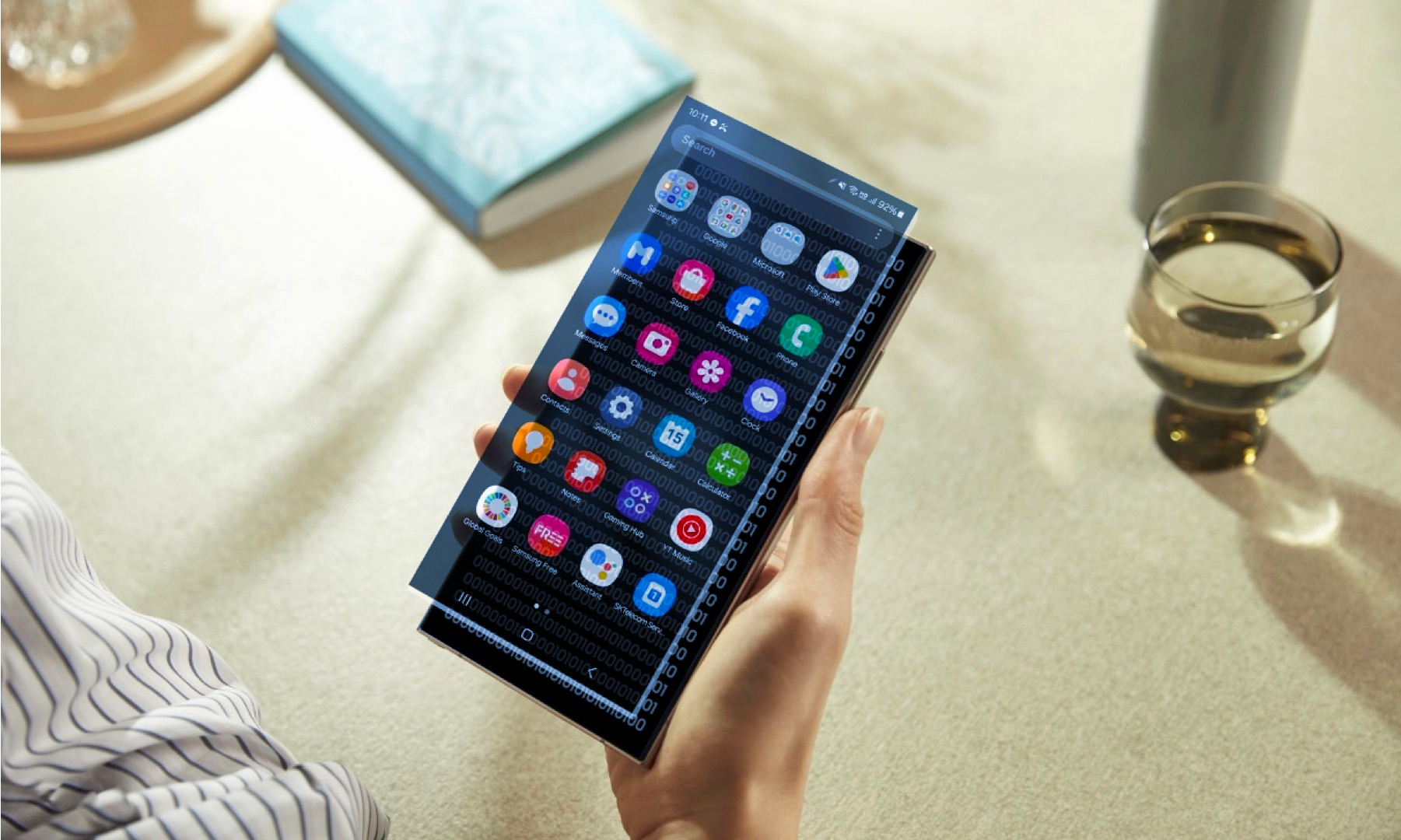 Person holding Samsung device with binary code beneath an app screen overlay